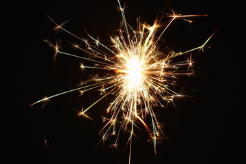 Christmas and New Year's illumination. Burning sparklers scatter bright exploding strips of sparks on a dark background.