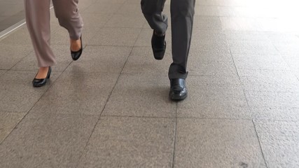 Legs of business people walking in a hurry together along the office corridor in the city