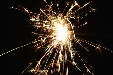 Christmas and New Year's illumination. Burning sparklers scatter bright exploding strips of sparks on a dark background.