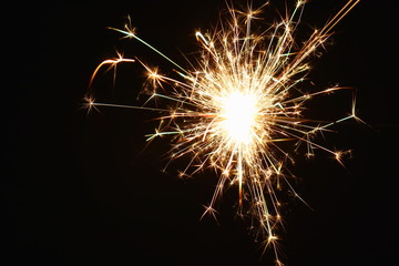 Christmas and New Year's illumination. Burning sparklers scatter bright exploding strips of sparks...