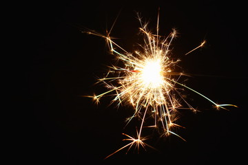 Christmas and New Year's illumination. Burning sparklers scatter bright exploding strips of sparks on a dark background.