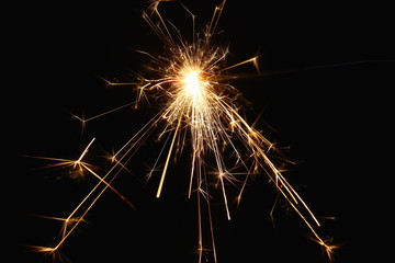 Christmas and New Year's illumination. Burning sparklers scatter bright exploding strips of sparks on a dark background.