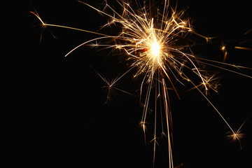 Christmas and New Year's illumination. Burning sparklers scatter bright exploding strips of sparks on a dark background.