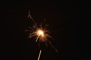 Christmas and New Year's illumination. Burning sparklers scatter bright exploding strips of sparks...