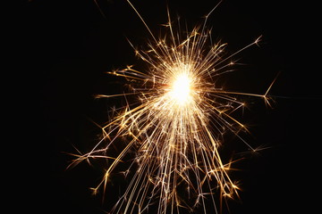 Christmas and New Year's illumination. Burning sparklers scatter bright exploding strips of sparks on a dark background.