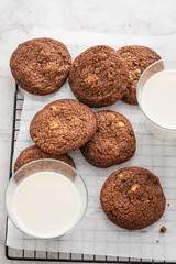 Closeup top view of a cup with milk, a chocolate cookie on white background.