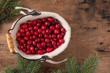 Cranberries in bowl on wooden background.