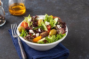 Salad of cucumbers, tomatoes, olives and fresh herbs with olive oil and pepper.