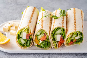Wrap sandwich, roll with fish salmon, vegetables and cheese. Grey background. Close up.