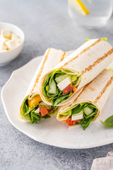 Wrap sandwich, roll with fish salmon, vegetables and cheese. Grey background. Close up.