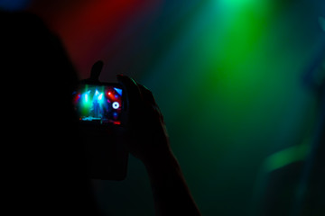 Fans rocks on your music with ambience light and hard beats filming the concert with phone