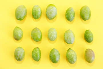 natural green fresh olives on a yellow background