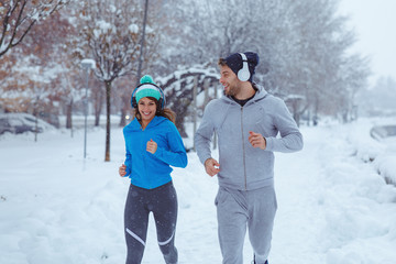 Fototapeta na wymiar Closeup of Young man and woman jogging on a snowy day in city