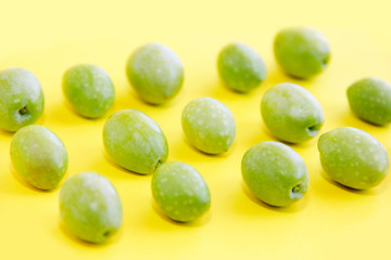 natural green fresh olives on a yellow background
