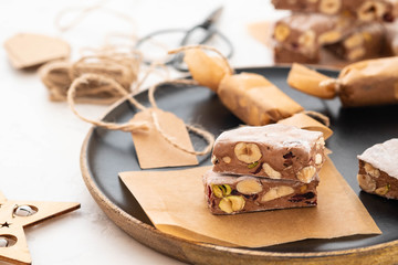 A variety of different nutty nougat in dark chocolate with roasted hazelnuts cut open to show the...