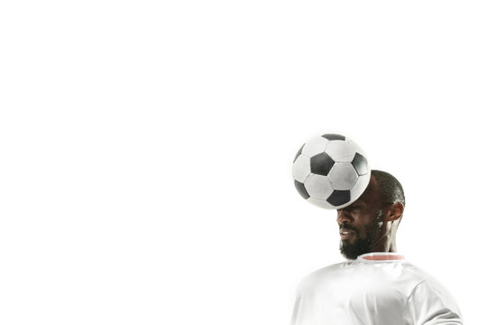 Close up of emotional african man playing soccer hitting the ball with the head on isolated white background. Football, sport, facial expression, human emotions, healthy lifestyle concept. Copyspace.