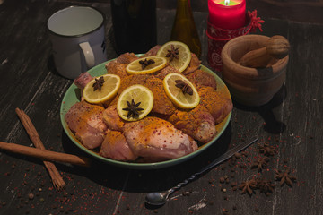 Raw chicken drumsticks spicy with lemon over a wood table with wine