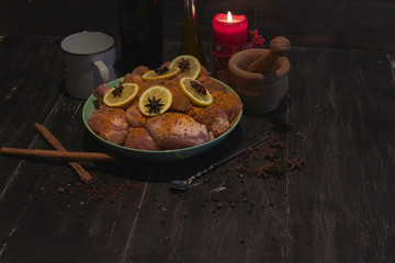 Raw chicken drumsticks spicy with lemon over a wood table with wine