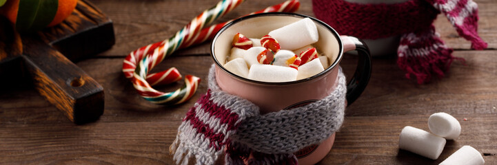 Christmas marshmallows and New Year decorations and sweet canes on a wooden background. Winter holidays, new year mood. Copy space. Close up. Banner.