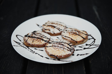 homemade chocolate pancakes served on a white plate over black texture background