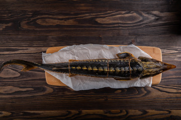 Large smoked sturgeon fish with head on wooden background.
