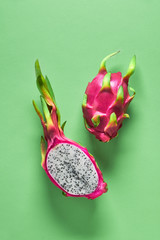Fresh organic dragonfruit (pitaya or pitahaya) cut in half on trendy vibrant green mint background....