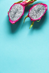 Fresh dragonfruit, pitaya or pitahaya, cut in half on blue mint background. Creative flat layout...