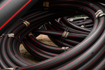 Black rubber or plastic pipes with a red lines as a construction material and equipment at building...