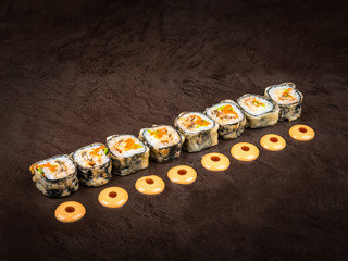 Serving of Japanese-style rolls arranged in a row on a dark background