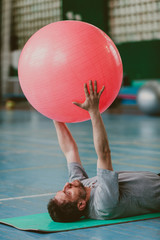 Naklejka premium Man performs exercise with big ball