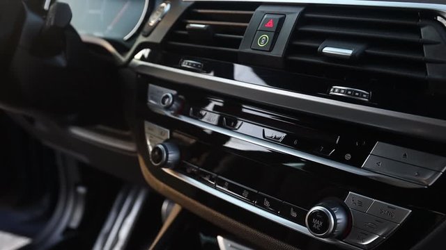 Music player, climate control buttons, emergency stop button. Dashboard of a premium car. Leather steering wheel. The interior of the car.