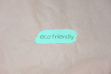 "Eco friendly" text on green and brown packing paper background. Eco friendly, sustainable living and zero waste concept. Flat lay, top view. 