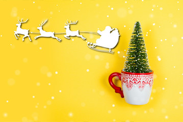 Christmas tree in a holiday mug with snow, Santa and reindeers graphics