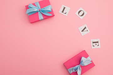 Valentines day concept with love word and gift box on pink background. Flat lay