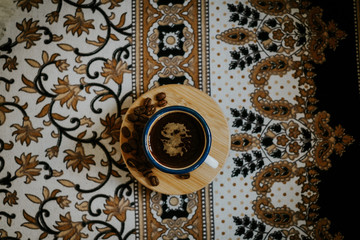 Top view of espresso cup and coffee beans on floral pattern