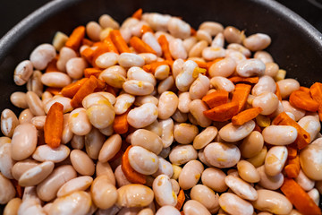 Carrots, garlic and beans in a pan before cooking. Close veiw