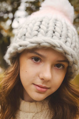   cute girl in a knitted hat looks in frame on a natural background