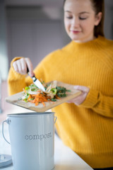 Woman Making Compost From Vegetable Leftovers In Kitchen