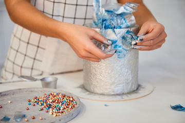Cropped view of confectioner decorating cake on board