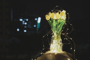 a glass jar with a bunch of tulips surrounded with a string of lights with golden warm lights...