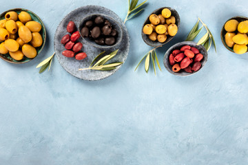 Olives flat lay overhead shot with a place for text. Black, green and brown olives of various sizes with leaves and copy space