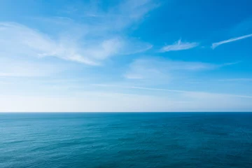 Fotobehang cloudy blue sky leaving for horizon above a blue surface of the sea © Nickolay Khoroshkov