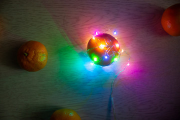 Tangerines and oranges and their skins are decorated with Christmas lights garland