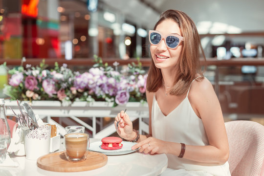Happy asian woman tasting delicious macaroon in cafe. Breakfast and french cuisine concept