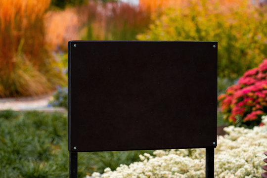 Blank Black Billboard With Empty Space on Park Or Garden Background. Canvas Board For Advertising Or Information Desk. Close Up