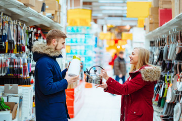 The guy and the girl choose a kettle in the supermarket.