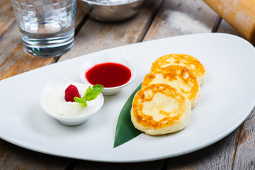 Traditional breakfast with coffee and cheesecakes, cottage cheese pancakes on a plate with syrup and jam.
