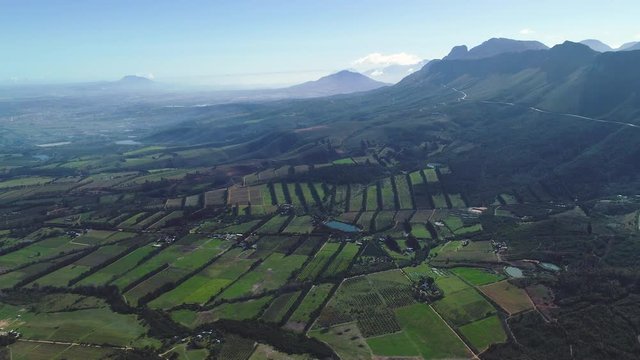 Aerial - Farms from above looking like patches stitched together, flying sidewards & road snaking up mountainside