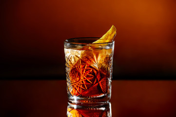 A glass of whiskey with ice on an orange brown background.