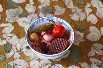 Red pickled cabbage in white bowl on wooden background